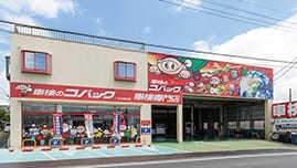 車検のコバック行方麻生店の外観。赤い看板とカラフルな壁画が印象的な建物。